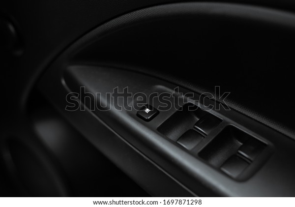 Close up of a door control panel in a new modern\
car. Arm rest with window control panel, door lock button, and\
mirror control.