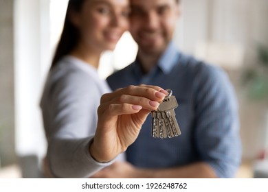 Close up of door key in woman hand. Happy millennial couple just moving into new home, buying house, getting mortgage loan approval, renting apartment and start living together. Property purchase