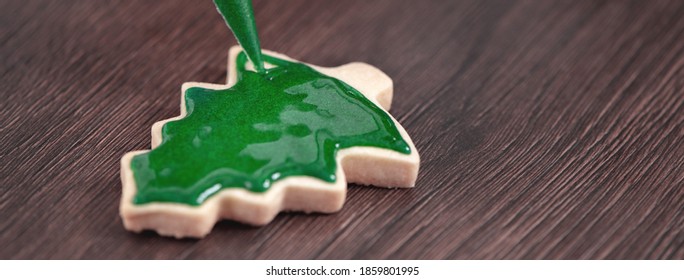 Close Up Of Drawing Gingerbread Christmas Tree Sugar Cookie On Wooden Table Background With Green Icing, Concept Of Holiday Celebration.