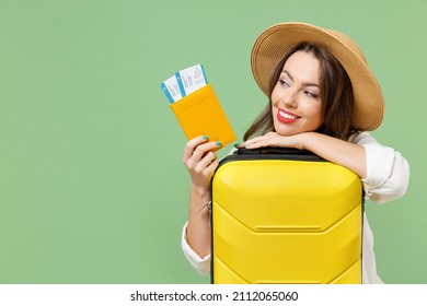 Close up dreamful fun tourist woman in casual clothes hat hold passport tickets yellow suitcase valise isolated on green background Passenger travel abroad weekend getaway Air flight journey concept. - Powered by Shutterstock