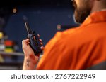 Close up of drilling barge technician using two way radio to coordinate emergency response procedures. Offshore platform employee communicating with technical team during night shift