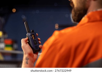 Close up of drilling barge technician using two way radio to coordinate emergency response procedures. Offshore platform employee communicating with technical team during night shift