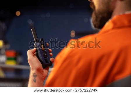 Close up of drilling barge technician using two way radio to coordinate emergency response procedures. Offshore platform employee communicating with technical team during night shift