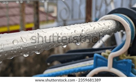 close up of drying poles and wet clothes hangers filled with raindrops