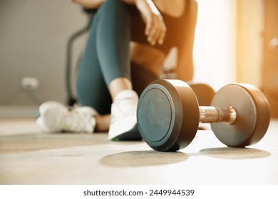 Close up Dumbbell on floor in gym with woman background. Object goal weightlifting bodybuilding.  - Powered by Shutterstock