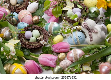 Close up of Easter assortiment of Easter eggs, spring flowers, and toys over white background