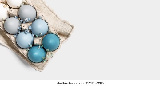 Close up Easter eggs pastel colored in egg box decorated small flowers. Minimal Easter celebration concept, dyed chicken egg with blue green color gradient in carton pack. Top view, copy space
