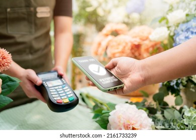 Close up of easy payment by credit card or smartphone application Greenhouse workers selling pottered flowers.Contactless payment with credit card customer at counter using QR code contactless payment - Powered by Shutterstock