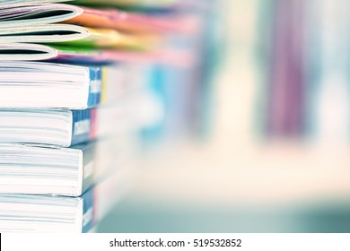Close up edge of colorful magazine stacking with  blurry bookshelf background for publication and publishing concept , extremely DOF 