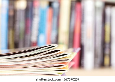 Close up edge of colorful magazine stacking with  blurry bookshelf background for publication and publishing concept , extremely DOF 