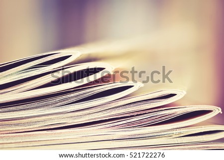 Close up edge of colorful magazine stacking with  blurry bookshelf background for publication and publishing concept , extremely shallow DOF  with vintage retro color tone