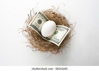 Close Up Of Egg And Money In Bird Nest Representing Retirement Nest Egg Or Savings.