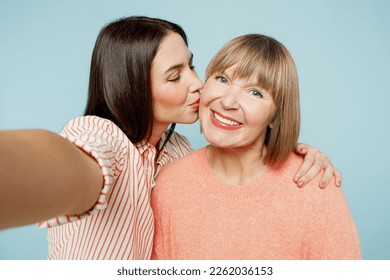 Close up elder parent mom with young adult daughter two women together wear casual clothes doing selfie shot pov on mobile cell phone kiss hug isolated on plain blue cyan background Family day concept - Shutterstock ID 2262036153