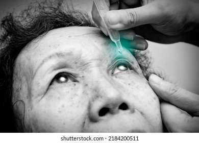 Close Up Of Elder Woman Drips Eye Drops Into Her Eyes With Green Spot On The Drop. Black And White Tone. Treatment For Eye Diseases. Healthcare Concept