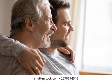 Close Up Of Elderly Father And Adult Grown-up Son Hug Look In Distance Planning Or Dreaming Together, Happy Hopeful Young Millennial Man Embrace Mature Dad Thinking Visualizing Good Future