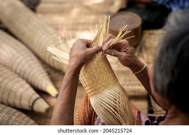 Close up of elderly hands manually weaving bamboo basket