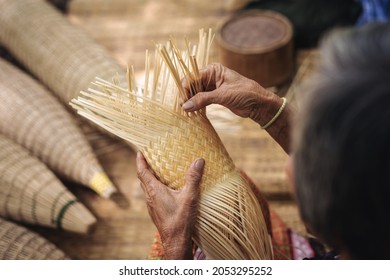 Close up of elderly hands manually weaving bamboo basket - Powered by Shutterstock