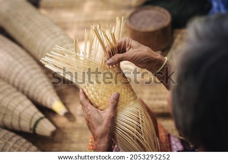 Close up of elderly hands manually weaving bamboo basket