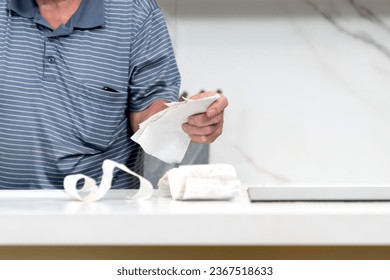 Close up of elderly man sitting at the table, stressed and confused by calculate expense from invoice or bills, have no money to pay mortgage or loan. High prices and spending money concept