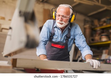 Close up of an elderly professional carpenter using circular saw machine for processing wood - Powered by Shutterstock