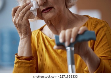 Close up of elderly woman crying and wiping eyes with tissue in therapy session - Powered by Shutterstock