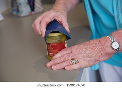 Close Up Of Elderly Woman Using An Aid To Open A Glass Jar. 