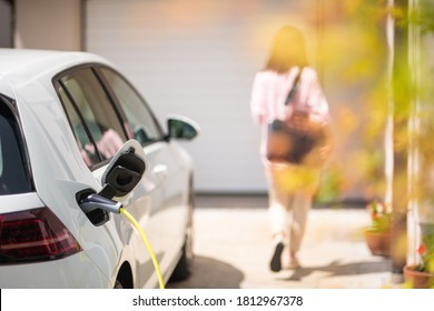 Close Up Of A Electric Car Charger With Female Silhouette In The Background