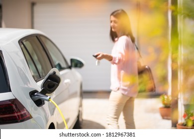 Close up of a electric car charger with female silhouette in the background, locking a car