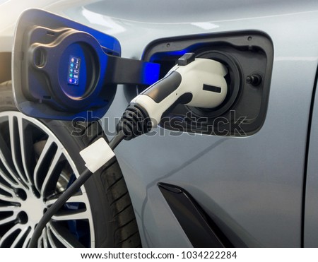 Close up of Electric car socket on process of charging an electric vehicle. Plug the charger Access to vehicle electrification.
