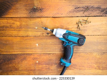 Close Up Electric Drill And Nails Left On Wooden Floor