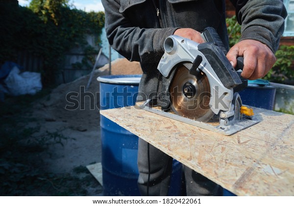 Close up electric saw to sawing wood board,\
solf focus. Plywood Cut by Circular Saw. Construction Worker and\
the Woodworking
