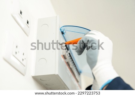 Close up electric screwdriver of electrician man in uniform maintenance or fixing switches socket circuit breaker electrical system. Technician fixing an electric fuse at home. Home service concept.