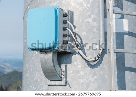 Close up of an electrical junction box attached to a galvanized steel wind turbine tower, ensuring safe and efficient power distribution