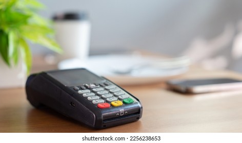 close up an electronic banking money machine with hot beverage cup on white table counter in coffee bar shop with copy space background for business and  technology of contactless payment concept
