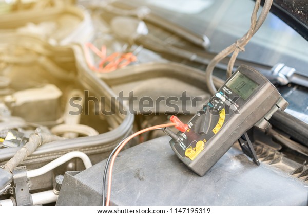 close up electronic multi meter device or tool\
during use for electric system check of car repair on automobile\
gasoline or diesel engine at\
garage