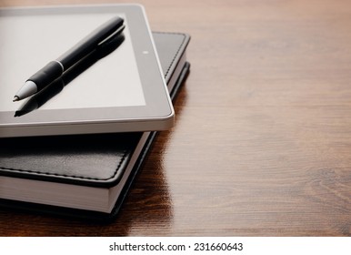 Close up Electronic Tablet Device on Notebook Resting on Wooden Table. Emphasizing Learning Concept.