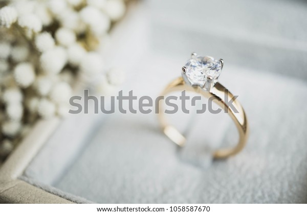Close\
up of elegant diamond ring in the box with white flower background.\
soft and selective focus.love and wedding\
concept.