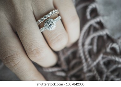 Close up of elegant diamond ring on woman finger with dark brown scarf background. soft and selective focus.Love and wedding concept.
