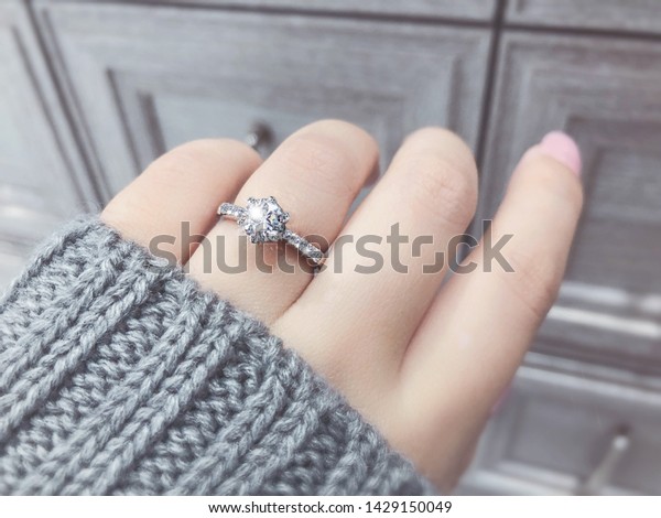 Close up of elegant diamond\
ring on the finger with gray Scarf background. Diamond\
ring.