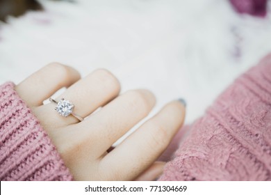 Close up of an elegant engagement diamond ring on woman finger with dark pink sweater winter clothe. love and wedding concept. - Shutterstock ID 771304669