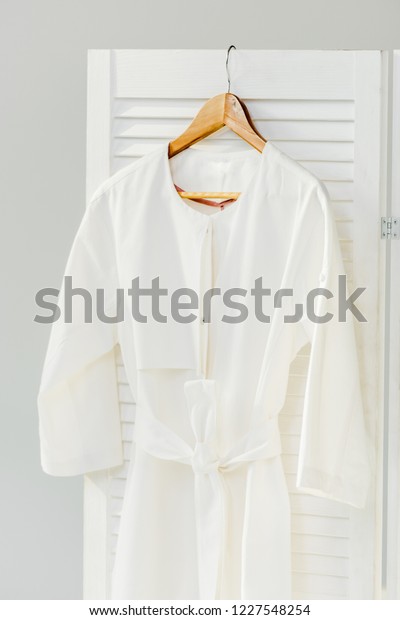 close up of elegant white dress hanging on wooden\
room divider isolated on\
grey