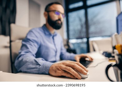 Close up of employee's hand using a computer mouse in a corporate company.