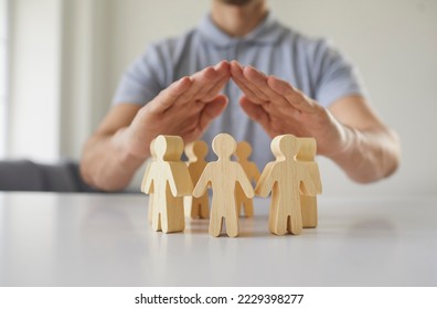 Close up employer holding hands over little pawn people. Responsible corporate business manager protects employees, guards their interests and creates equal and safe environment for developing talents