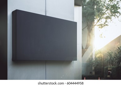 Close Up Of Empty Black Poster On Concrete Building. Trees And Sunlight In The Background. Mock Up