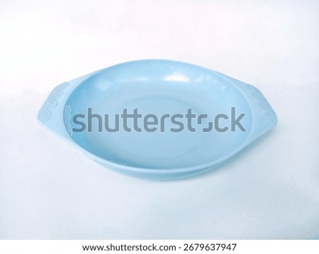 Close up of an empty blue ceramic plate with handles isolated on white background.