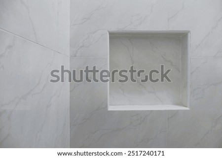 Close up of empty built-in shower caddy in wall recess in bathroom. Modern elegant bathroom interior with marble wall tiles. Display shelf for toiletries logo branding mockup.
