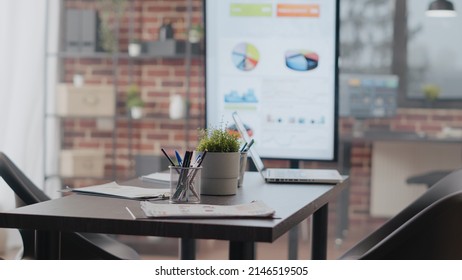 Close Up Of Empty Desk Used For Business Meeting In Office. No People In Boardroom With Data Analysis On Monitor And Charts On Papers For Financial Presentation At Work. Startup Company