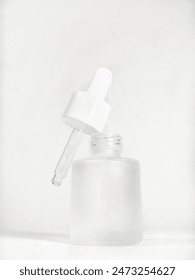Close up An empty dropper sits on the neck of a white frosted open bottle isolated on a white background. Cosmetic product mock up