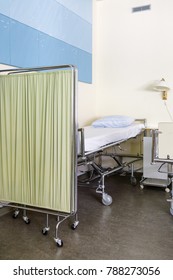 Close Up Of Empty Hospital Bed Behind Bed Screen In Hospital Ward With No People