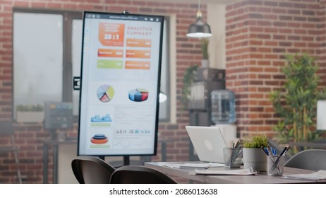 Close Up Of Empty Meeting Table In Business Office With Analysis Presentation On Monitor. Nobody In Startup Space Used For Research Work And Project Planning, No People At Company Job.